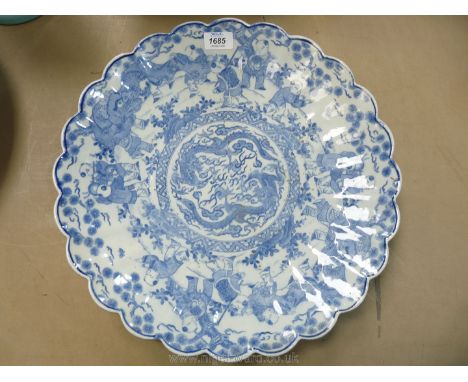 A large blue and white oriental Dish, having scalloped edge, central panel with dragon decoration surrounded by scene with yo