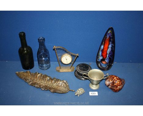 A small box of miscellanea including Harp clock, metal cup, brass leaf dish, clear and green glass bottles, shell, etc