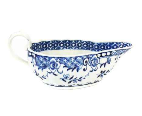 A Worcester Porcelain Sauceboat, circa 1775, of shallow fluted form and with scrolling handle, painted in underglaze blue wit
