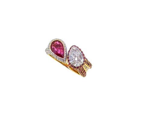 A contemporary ruby and diamond ring, rubover set pear shaped brilliant cut diamond, surrounded by pavé set round faceted rub