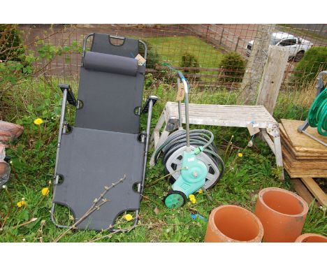 A work bench stand, hose & reel and a lounger.