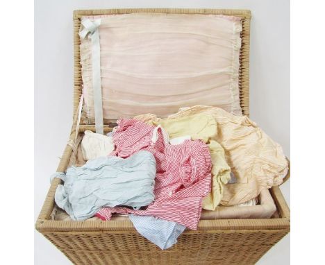A vintage wicker nursery basket containing assorted mid and earlier 19th century baby clothes, to include smocked items, romp