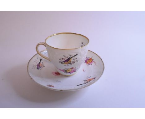 An early 19th century English porcelain teacup and saucer, with moulded decoration and painted birds, flowers and foliage, si