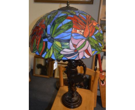 A bronzed figural table lamp, with a Tiffany style glass shade, 84 cm high   Condition report  Modern