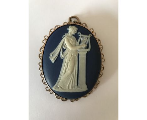 A Wedgwood cameo of a classical female playing harp in a yellow metal surround marked 9ct. 7.5 x 6cms. 