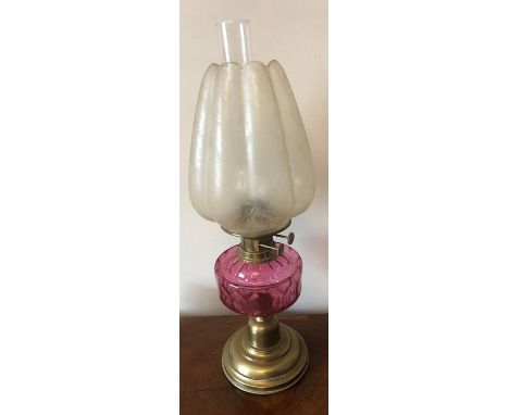 A vintage brass and glass oil lamp with cranberry glass well, shade decorated with peacock feather pattern. 56cms h. Glass ch