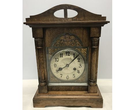 Oak cased mantle clock with key and pendulum. Brass cherub decoration around dial. 37cms h x 26cms w base. 