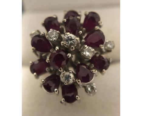 A ruby and diamond cocktail ring set with seven round brilliant cut diamonds and twelve mixed cut dark rubies set in 14 ct wh