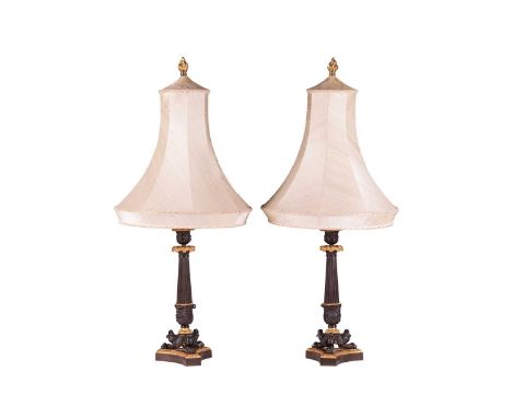 A pair of Louis Phillipe style patinated and parcel gilt table lamps, with acanthus mantel drip pans, reeded columns over ant