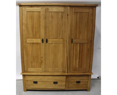 A modern oak bedroom suite comprising light oak triple wardrobe on two-drawer base, height 195cm, width 160cm, a chest of two