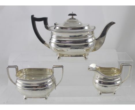 A George V hallmarked silver three-piece tea service with cast beaded rim, raised on four ball feet, William Hutton &amp; Son