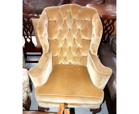 A Georgian-style wing-back armchair with button-back upholstery in a tan-coloured velour, on shell carved mahogany cabriole l