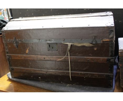 A domed-top travel trunk with wooden banding containing a collection of military equipment and a vintage wooden trunk (2).