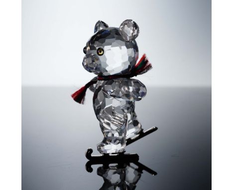 This charming Swarovski Kris Bear figurine captures the joyful spirit of winter, featuring a clear faceted crystal bear weari