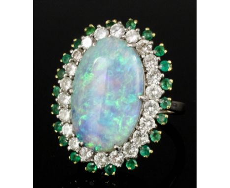 A modern 18ct white gold mounted opal, diamond and emerald ring, set with an oval opal, 21mm x 13mm x 6.3mm deep, within a bo