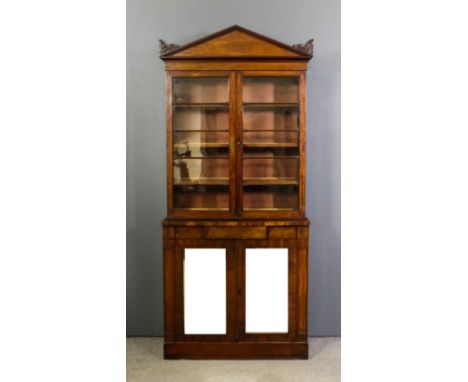 A William IV mahogany bookcase of architectural design the upper part with angled cornice with carved brackets, fitted three 