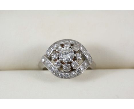 A DIAMOND CLUSTER RING the central brilliant-cut diamond is set within a surround of eight circular-cut diamonds and an outer