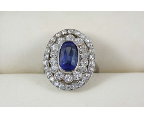 A SAPPHIRE AND DIAMOND CLUSTER RING the oval-shaped sapphire is set within a double surround of graduated old brilliant-cut a