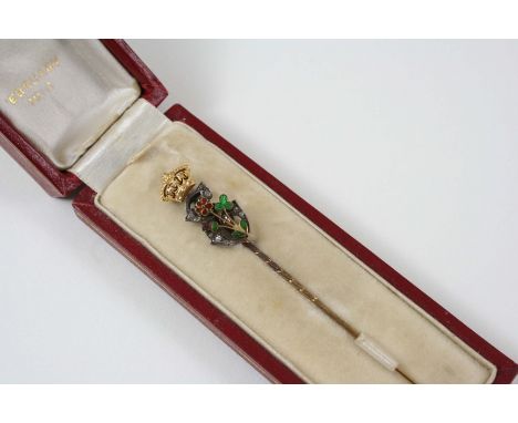 A DIAMOND, ENAMEL AND GOLD STICK PIN formed as a rose-cut diamond E with applied floral enamel decoration below a gold crown.