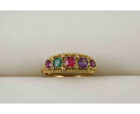 A GOLD AND GEM SET RING set with assorted gem stones, including an emerald, amethyst and ruby. Size K.