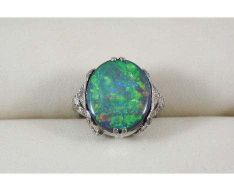 AN EARLY 20TH CENTURY OPAL AND DIAMOND CLUSTER RING the oval solid black opal is set within a surround of two triangular-shap