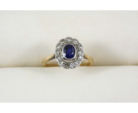 A SAPPHIRE AND DIAMOND CLUSTER RING the oval-shaped sapphire is set within a surround of single-cut diamonds in 18ct. gold an