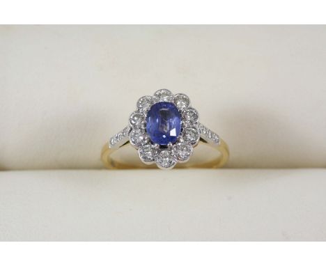 A SAPPHIRE AND DIAMOND CLUSTER RING the oval-shaped sapphire is set within a surround of ten circular-cut diamonds, with thre