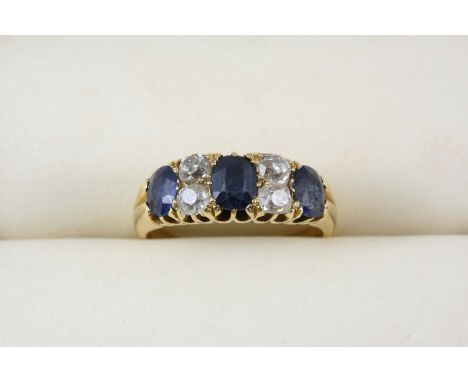 A SAPPHIRE AND DIAMOND RING the three oval-shaped sapphires are set with four cushion-shaped diamonds in 18ct. gold. Size R.