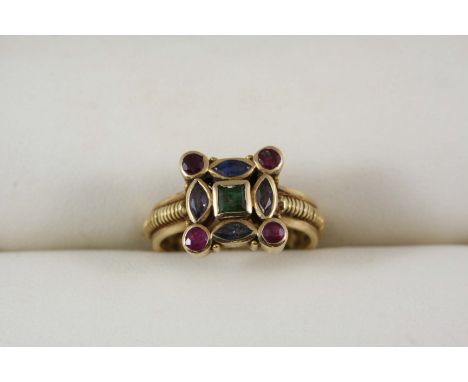 A GOLD AND GEM SET RING centred with a square-shaped emerald within a surround of marquise-cut sapphires and four circular-cu