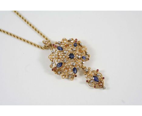 AN 18CT. GOLD AND GEM SET BROOCH PENDANT the openwork scrolling design is centred with an circular-cut sapphire within a surr