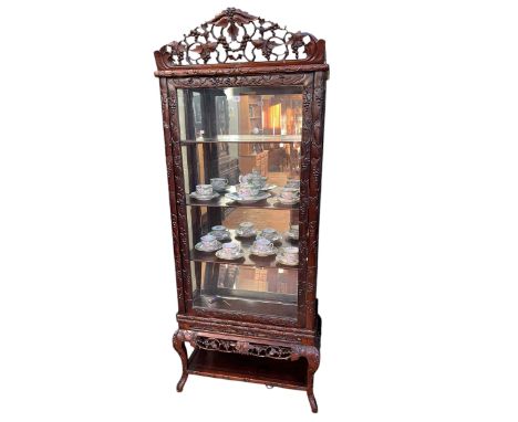 Chinese carved hardwood display cabinet on stand having scrolled fruit and leaf crest and internal mirror panelled back, 193c