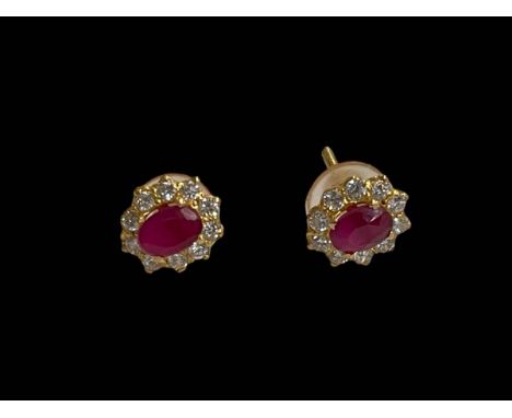 Pair ruby and diamond cluster earrings in yellow gold, each oval ruby with ten diamond border.