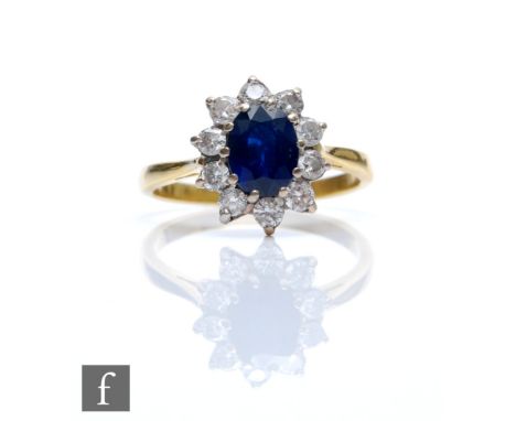 An 18ct hallmarked sapphire and diamond cluster ring, central oval claw set sapphire, length 8mm, within a border of ten bril