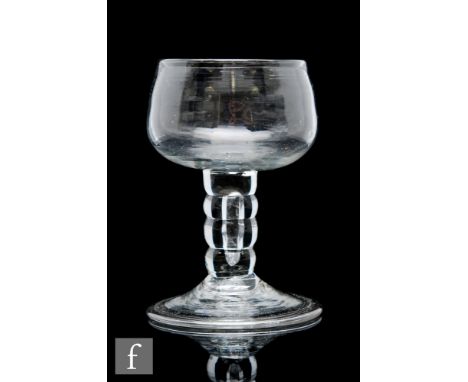 An 18th Century drinking glass circa 1740, the ovoid bowl raised to a four section bobbin stem with internal tear above a fol