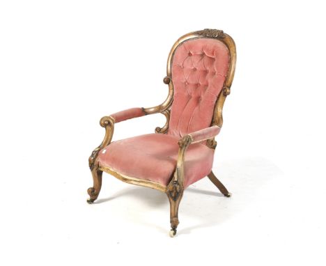A Victorian wooden framed button back open armchair. Upholstered in pink velvet, with carved decoration, on ceramic casters. 