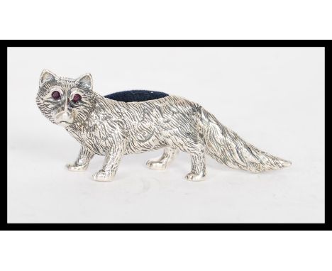 A stamped 925 silver pincushion in the form of a fox having a blue cloth cushion to its back and ruby eyes. Weight 24.7g. Mea