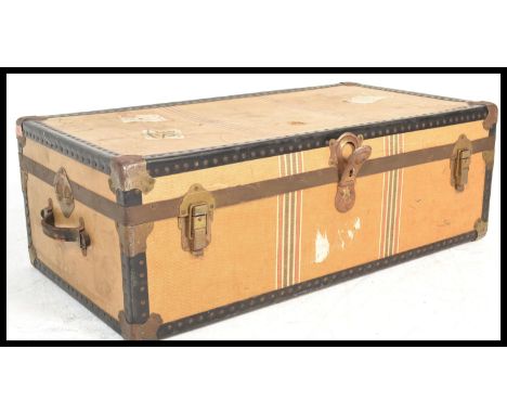 A vintage retro early 20h Century suitcase trunk being canvas and brass bound in a tan colourway. The hinged lid opening to r