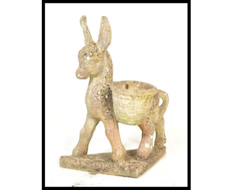 A vintage 20th Century well weathered reconstituted stone garden sculpture modelled as a donkey, the donkey with two pots acr