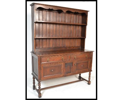 An early 20th Century 1920's oak dresser raised on block and turned legs with two drawers over two cupboards having brass dro