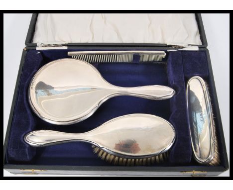 A vintage early 20th Century hallmarked silver brush set consisting of two brushes, mirror and comb complete in original case