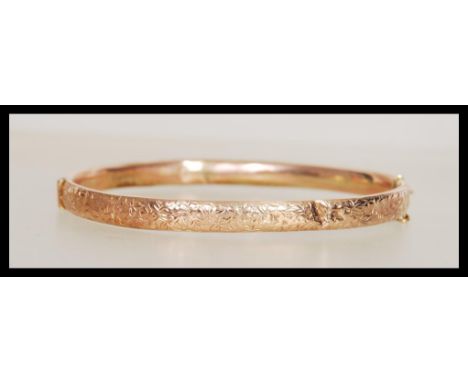 A hallmarked early 20th Century Edwardian 9ct gold bangle bracelet having a hinged opening and safety chain. Hallmarked Birmi