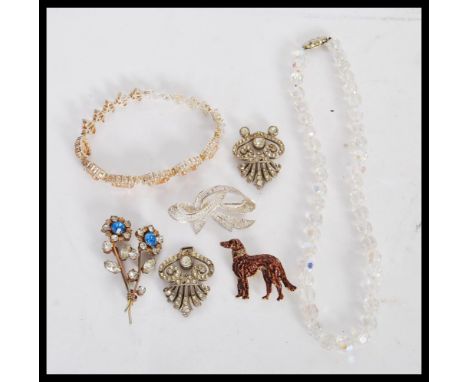 A selection of vintage costume jewellery to include a floral rhinestone brooch, a cold painted dog brooch with a red stone ey