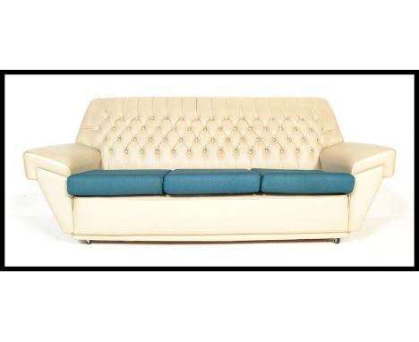 A vintage retro 20th Century sofa of Chesterfield type having button back upholstered in white with shaped arms and blue cush