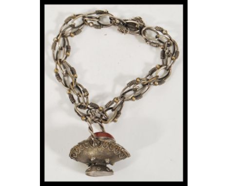 A stamped 800 silver bracelet having decorative links with rope chain detailing with a charm basket set with a carnelian cabo