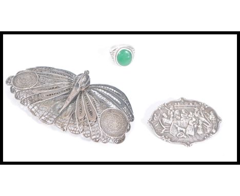 A large antique silver filigree brooch in the form of a butterfly along with a silver brooch depicting a Dutch m,aster scene 