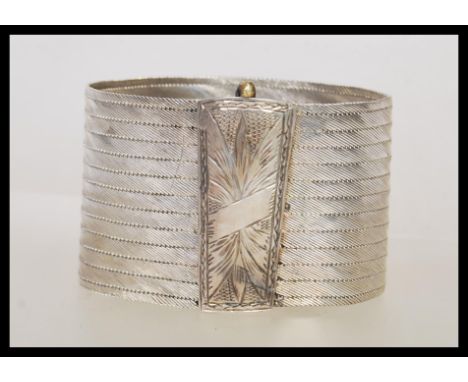 A stamped 900 silver ethnic style bangle bracelet having a rectangular clasp to the front with engraved decoration. Measures 