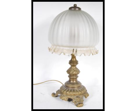 An early 20th Century heavy brass table lamp of scrolled form having a bulbous frosted glass shade. Measures 47 cm high x 24 