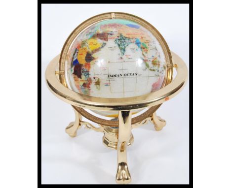 A vintage 20th Century desk top globe having a gilt brass frame with semi precious lapis lazuli and other stone inlay and com