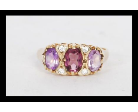 A hallmarked 9ct gold three stone amethyst ring in a Gypsy setting having white stones spacers. Weighs 3.5 grams size O.