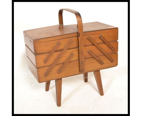 A vintage 20th Century beech wood concertina metamorphic action sewing / work box, carry handle to the top raised on tapering